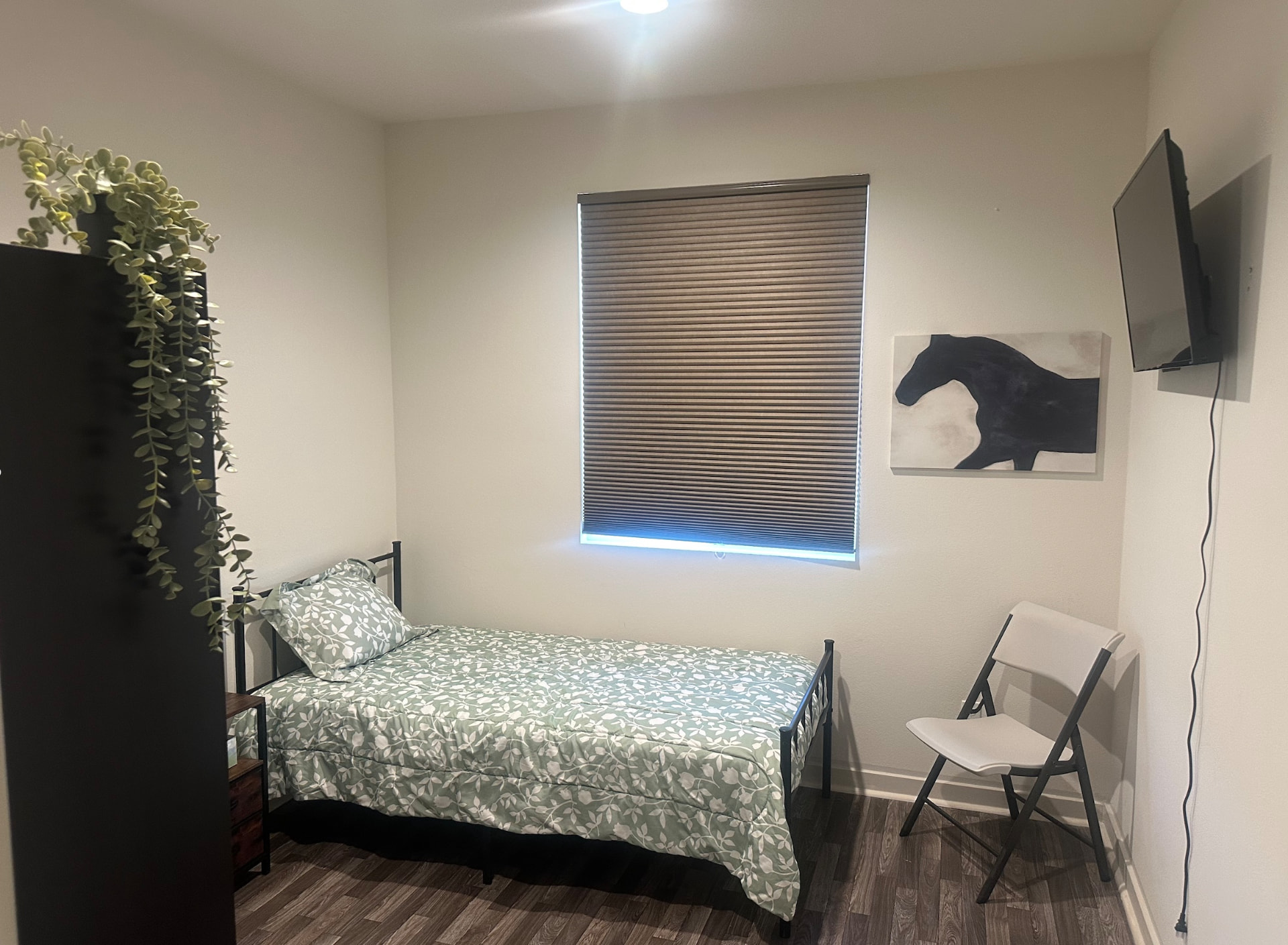 Private resident room with a window, wall television and reading chair