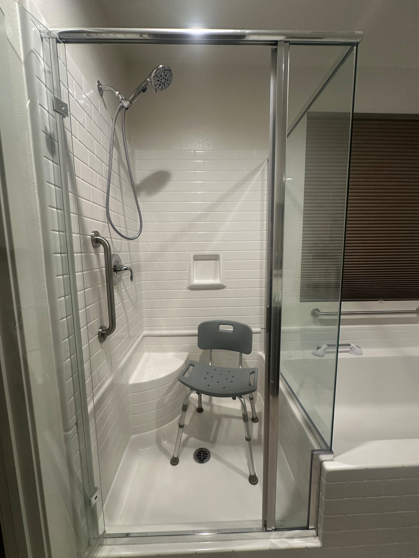 Accessible walk-in shower with a grab bar and shower chair