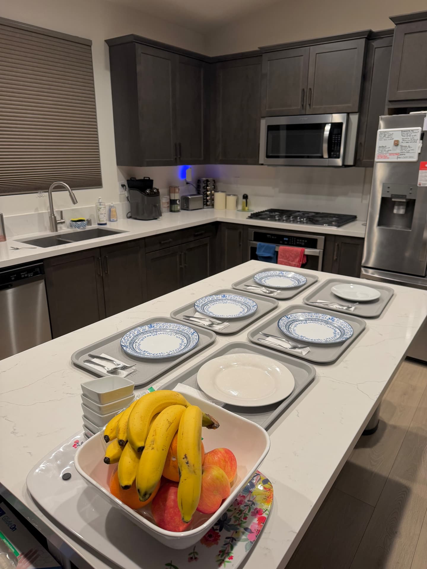 Kitchen island with meal trays set for residents and a bowl of fresh fruit