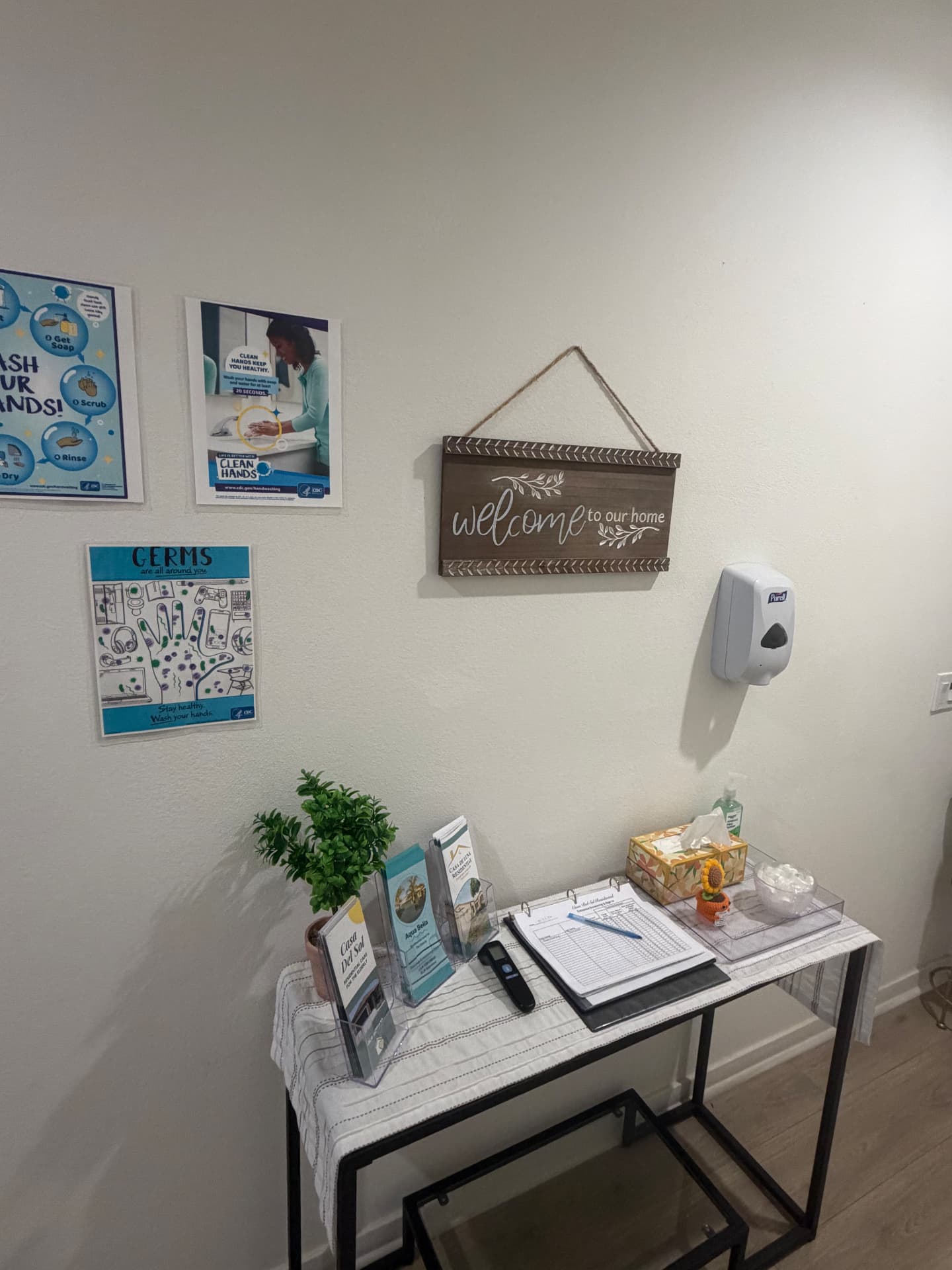 Entry sign-in table with brochures, sanitizer and a "welcome to our home" sign