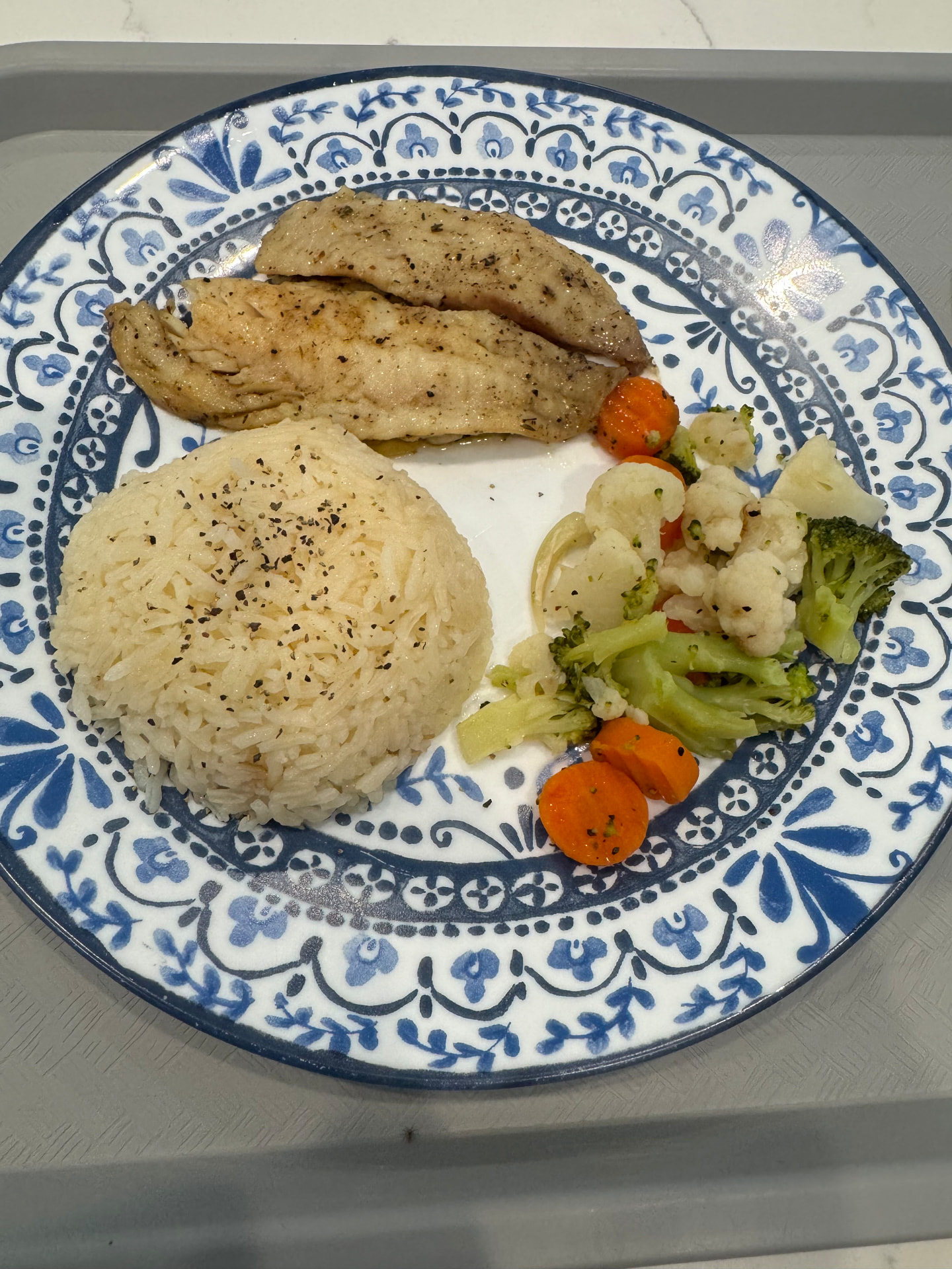Baked fish with rice and steamed vegetables on a resident meal tray
